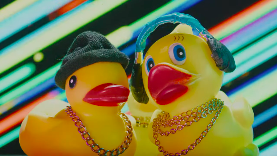 Two rubber ducks wearing gold chains, one wearing a beanie and the other wearing headphones,