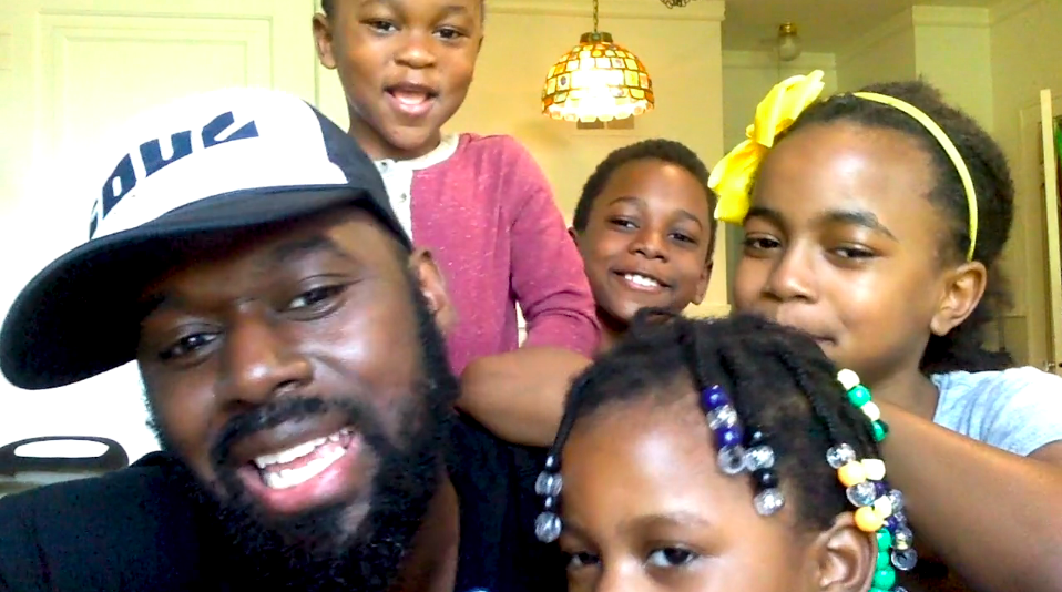 View of a dad and four children as through a webcam, close up to the camera and smiling